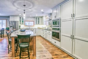 After remodel with wood floors, large open space, recessed lighting, large island with bar stools, and light cabinetry, and built-in appliances