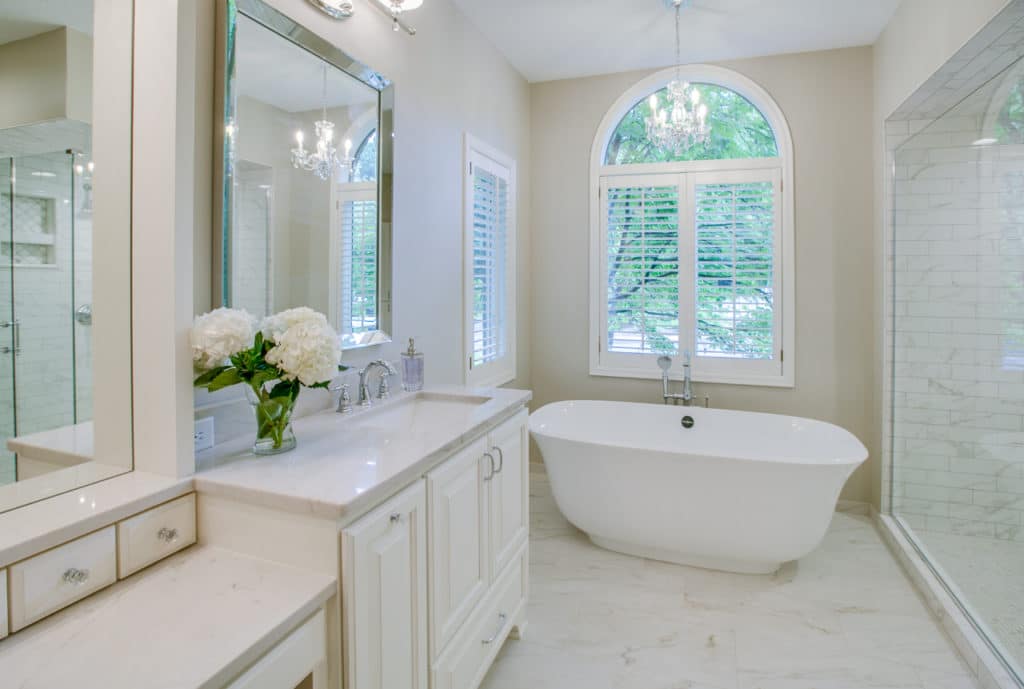 Remodeled bathroom with large arched window over standalone white tub.