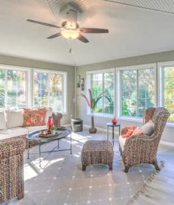 Sunroom addition with rows of large windows, a ceiling fan, patio furniture, and a gray rug.