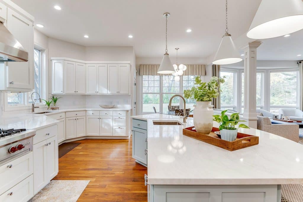 kitchen remodel with white countertops, white cabinets, wood floors, and recessed lighting.