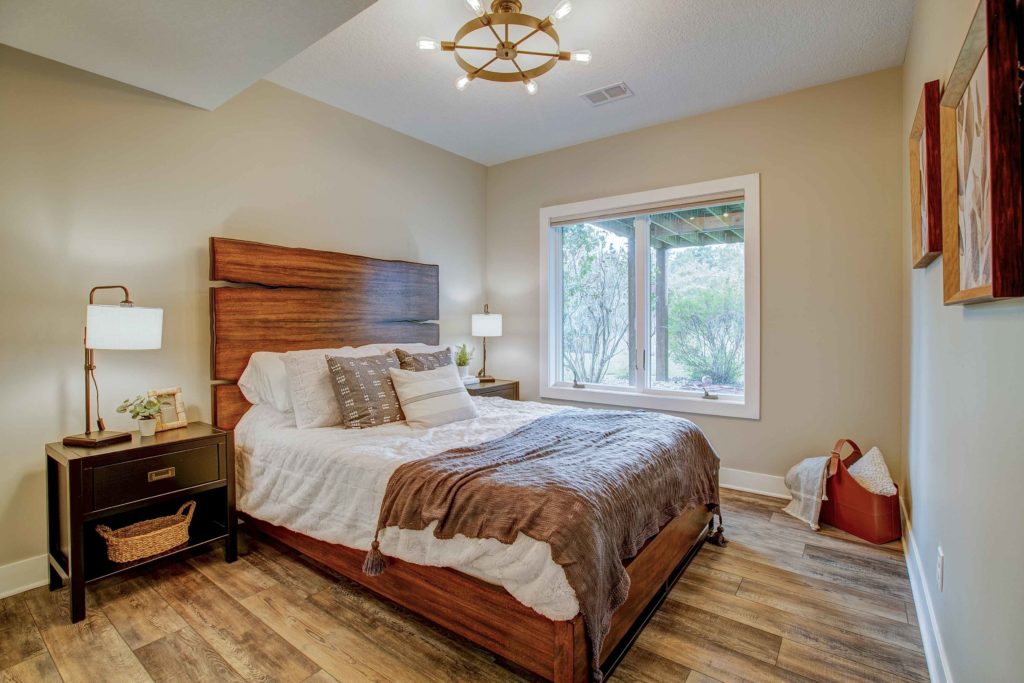 Bedroom remodeled in Woodbury, Minnesota, with wood floors, large casement window, and beige walls.