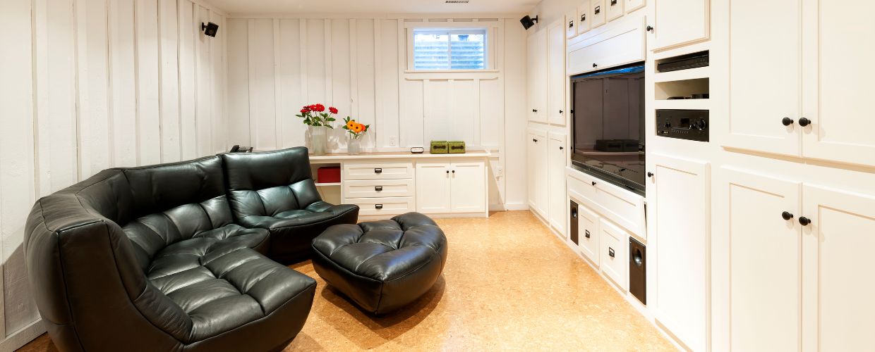 refinished basement with black couch and tv